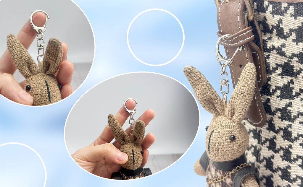 Close-up of a brown knitted bunny keychain with black eyes and stitched mouth, attached to a bag.