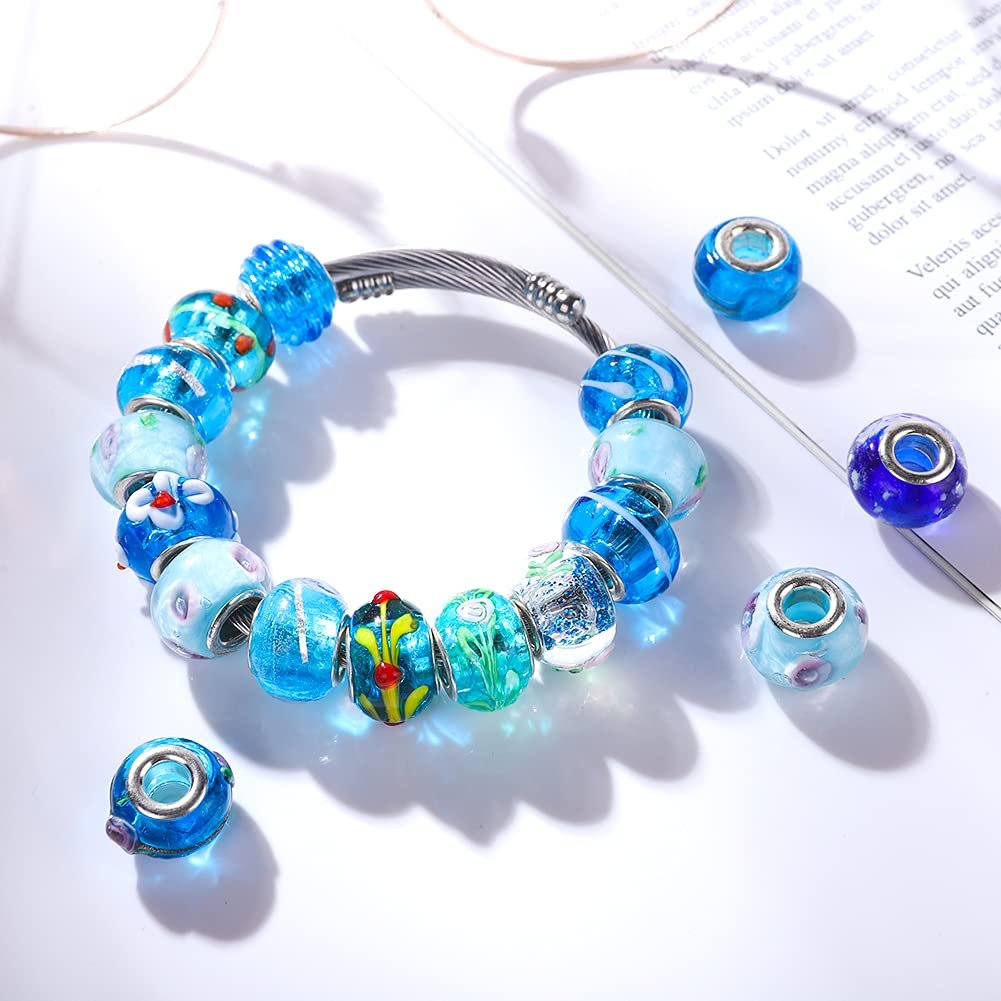Murano style large hole glass beads in various blue shades arranged on a bracelet and scattered around, with a book in the background.