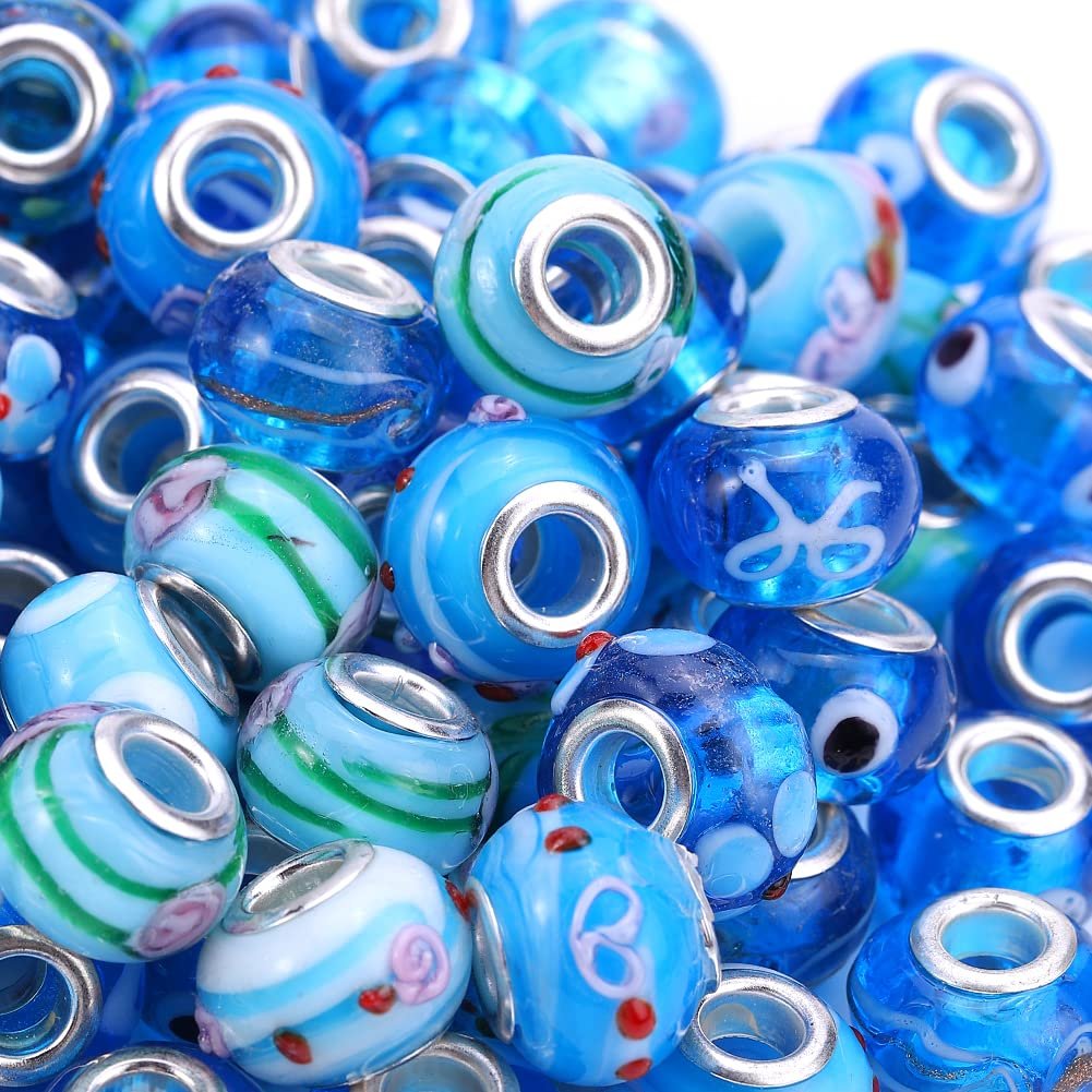 Pile of aqua and blue Murano style glass beads with silver-tone brass cores, featuring various decorative patterns.