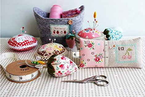 Sewing notions including pincushions, thread, scissors, and measuring tape on a checkered cloth.
