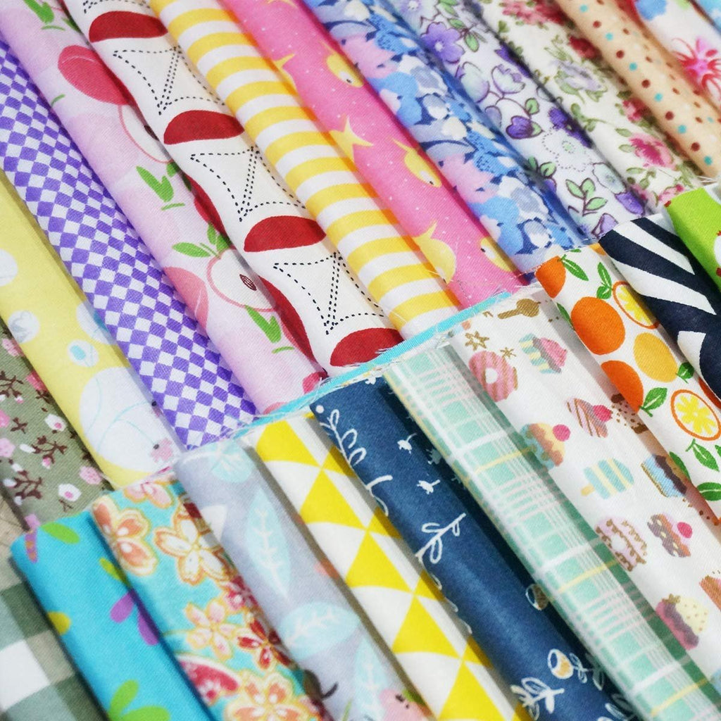 Assorted pre-cut cotton fabric squares with various patterns including fruits, flowers, and geometric designs, neatly rolled.