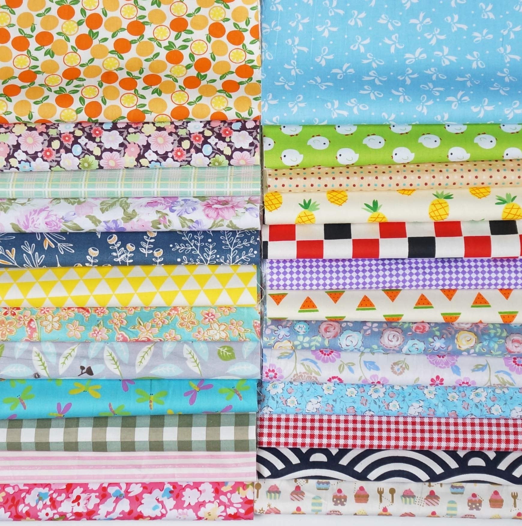 Stack of assorted pre-cut cotton fabric squares with various patterns including fruits, flowers, and geometric designs.
