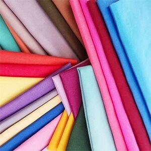 Stack of precut solid color cotton quilting fabric squares in various shades, fanned out.