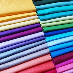 Stack of precut solid color cotton quilting fabric squares in various shades of yellow, purple, blue, green, and pink.