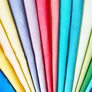 Fan of precut solid color cotton quilting fabric squares in various bright hues, arranged diagonally.