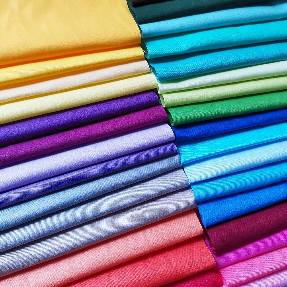 Stack of precut solid color cotton fabric squares in various shades of yellow, purple, blue, green, and pink.
