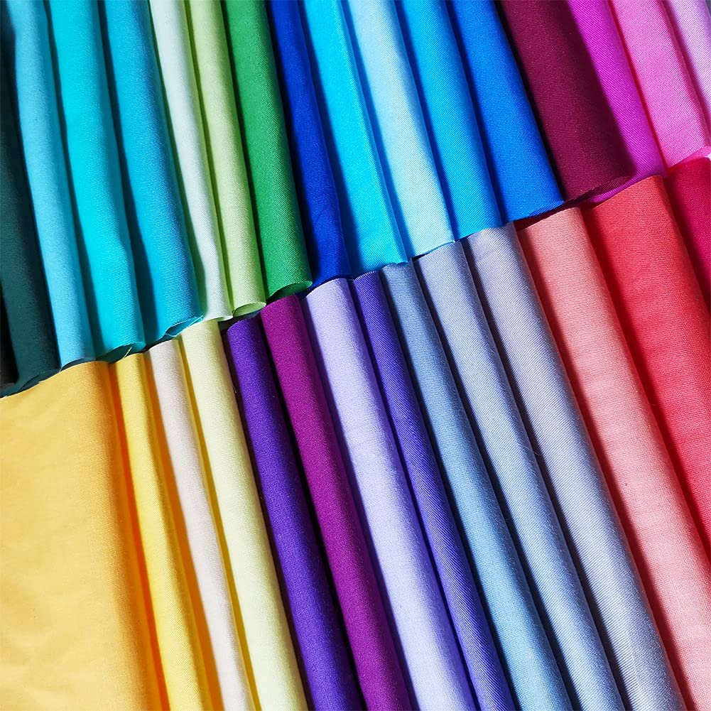 Assortment of precut solid color cotton fabric squares neatly folded in rows, showcasing a vibrant rainbow of colors.