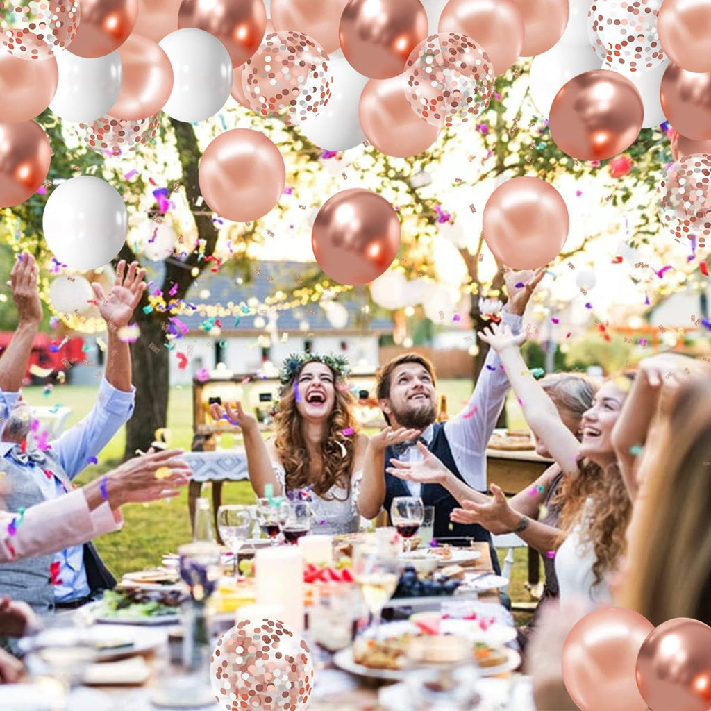 Rose gold, white, and confetti balloons floating above a wedding reception with guests throwing confetti.