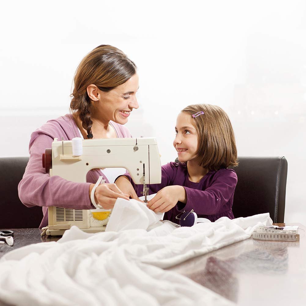 Mother and daughter smiling while sewing on a domestic sewing machine with white fabric.