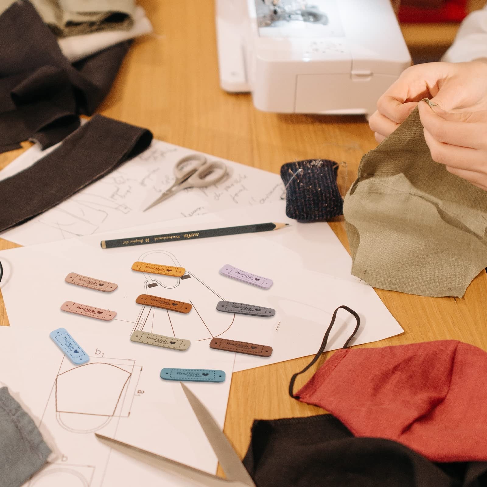Crochet faux leather tags in various colors laid out on sewing patterns with scissors and fabric.