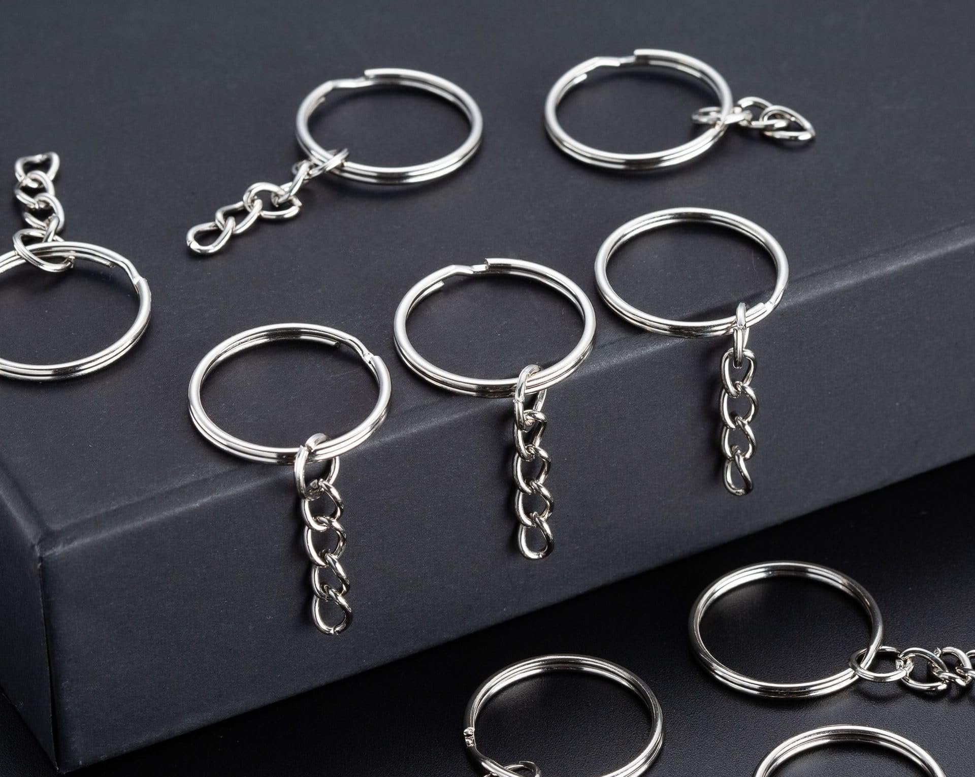 Silver split round keychain rings with chains and jump rings on a dark surface