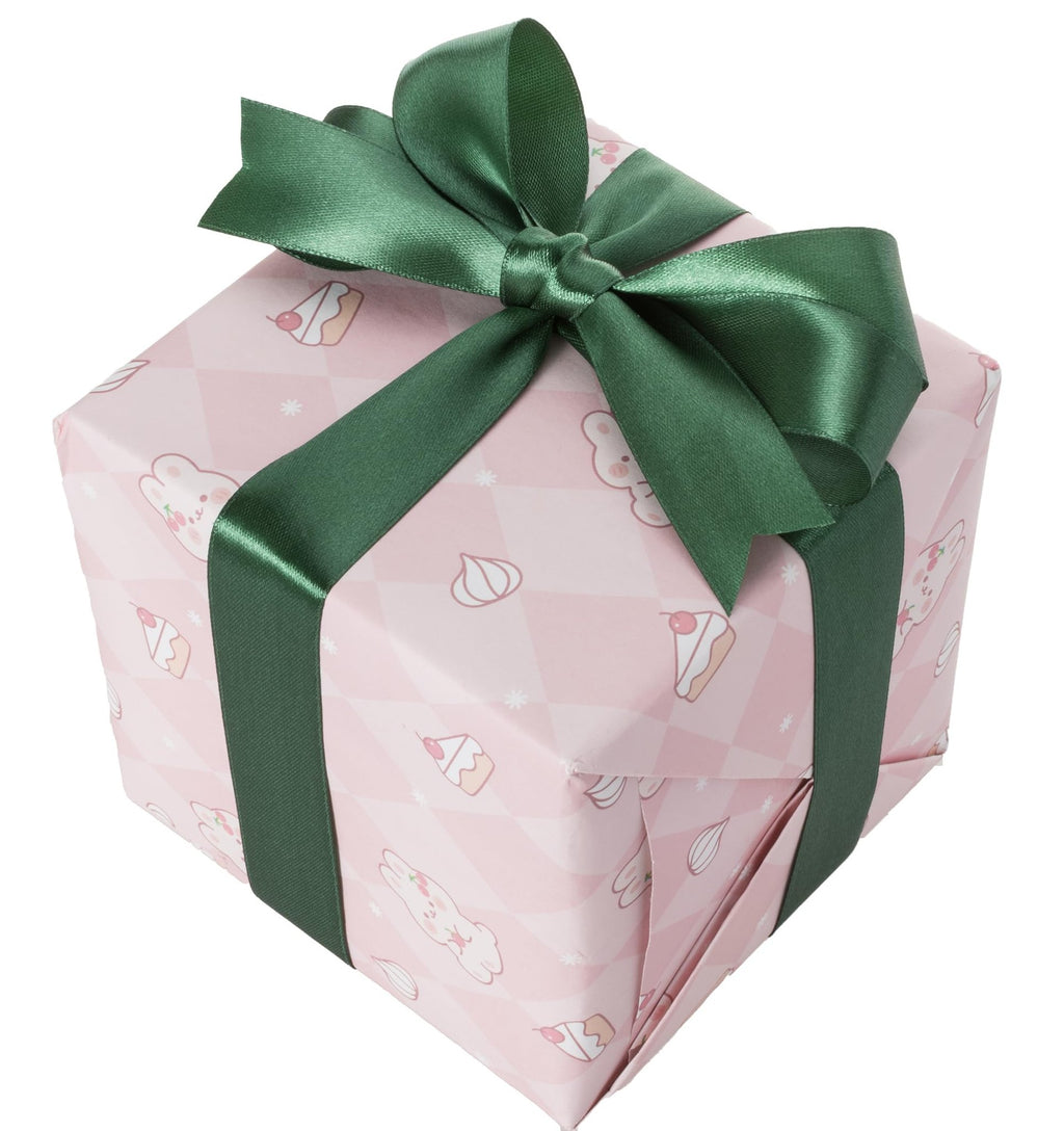 Gift-wrapped box with green ribbon and bow, decorated with pink paper featuring cartoon desserts and bunnies.