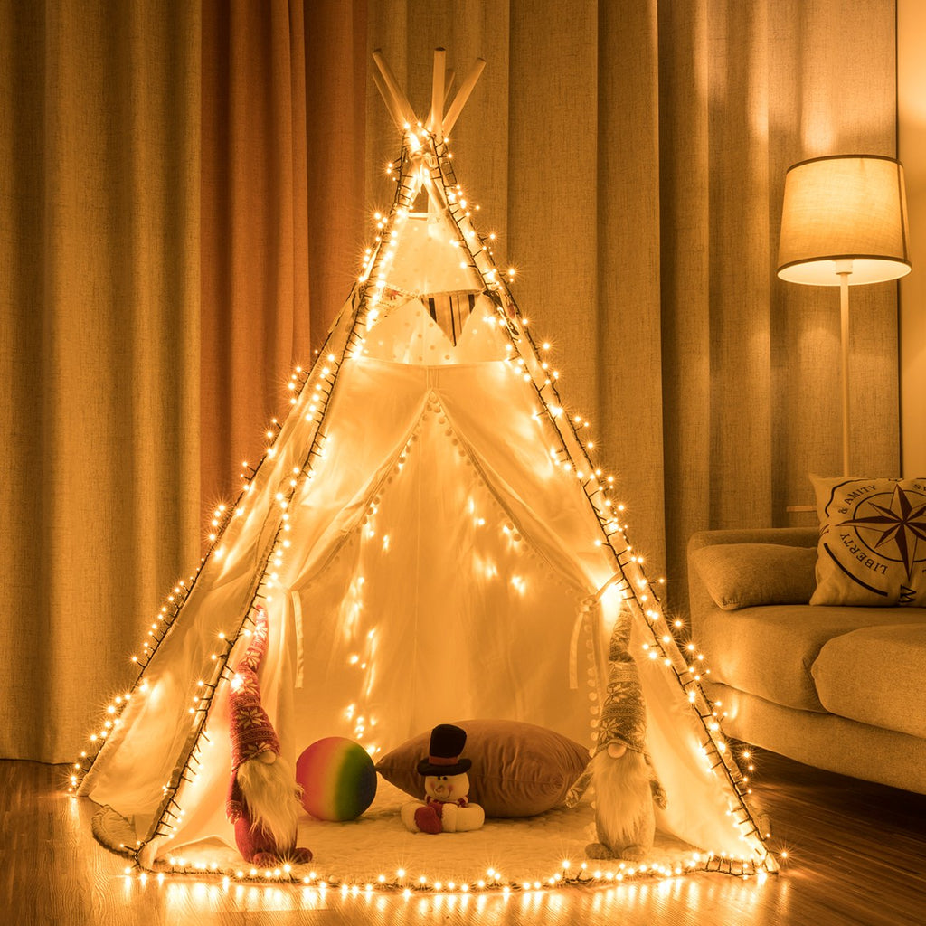 White teepee tent decorated with warm white string lights, with gnomes, a snowman plush, and a ball inside.
