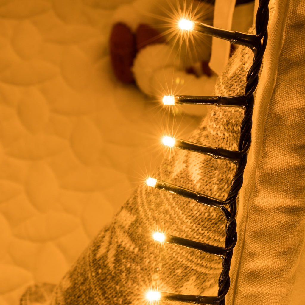 Close-up of warm white LED string lights with a festive, cozy background.