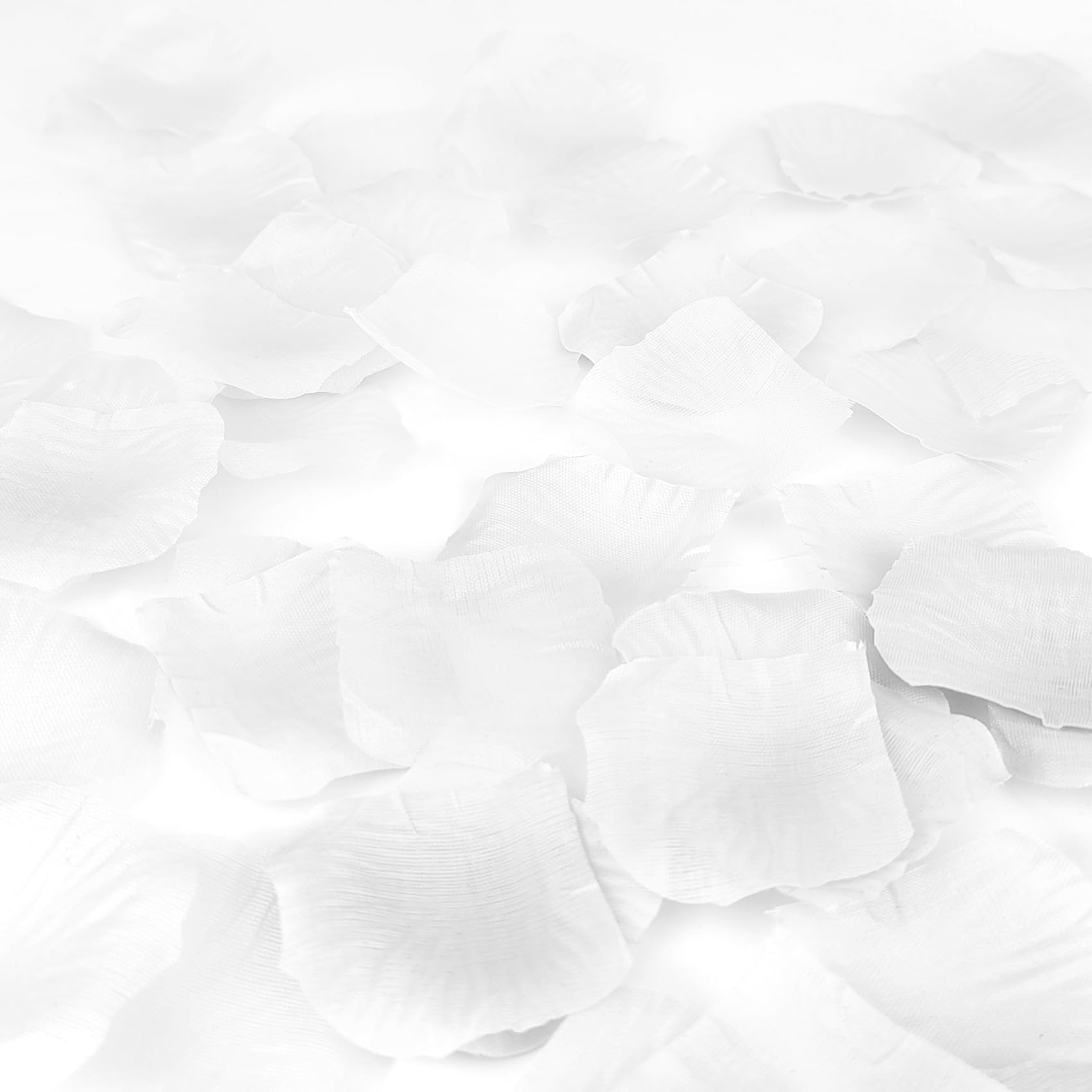Scattered white artificial rose petals made of silk fabric, close-up view