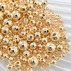 Close-up of a pile of small, round, gold-colored metal spacer beads with visible holes for stringing.