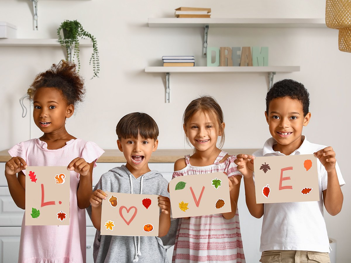 Four children hold up signs with fall-themed stickers and letters spelling 'LOVE'.