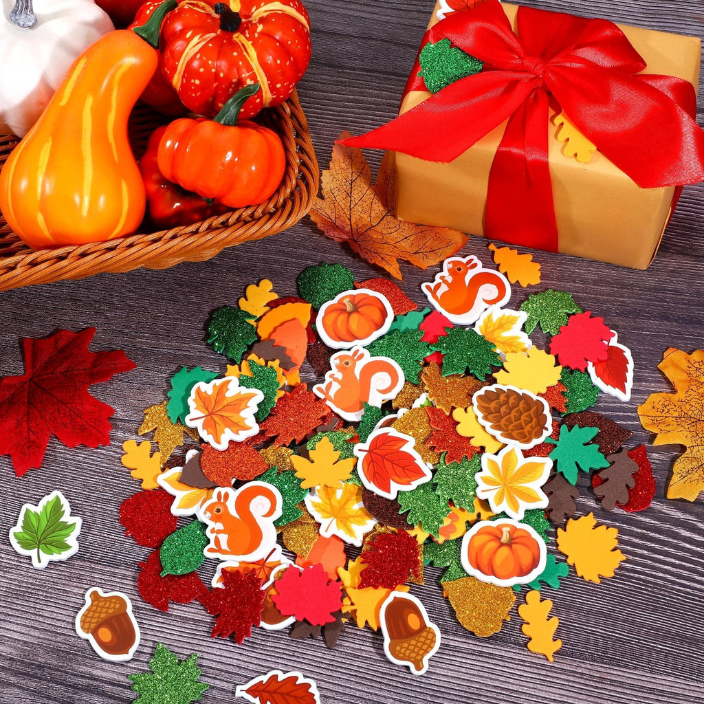 Fall leaf foam stickers scattered with pumpkins, squirrels, acorns, and a gift box on a wooden surface.