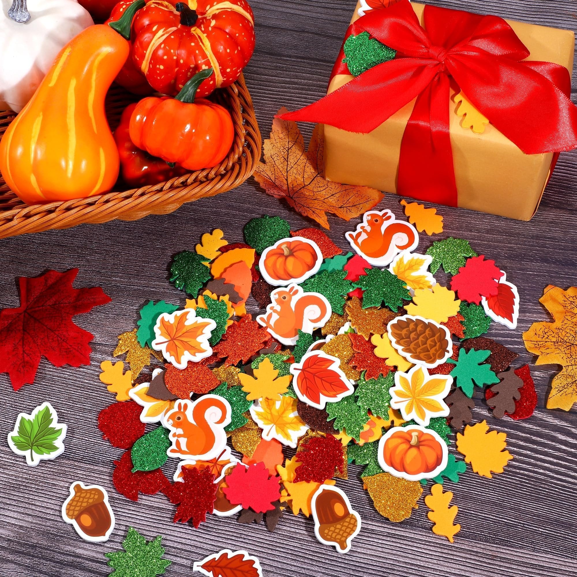 Fall leaf foam stickers scattered with pumpkins, squirrels, acorns, and a gift box on a wooden surface.