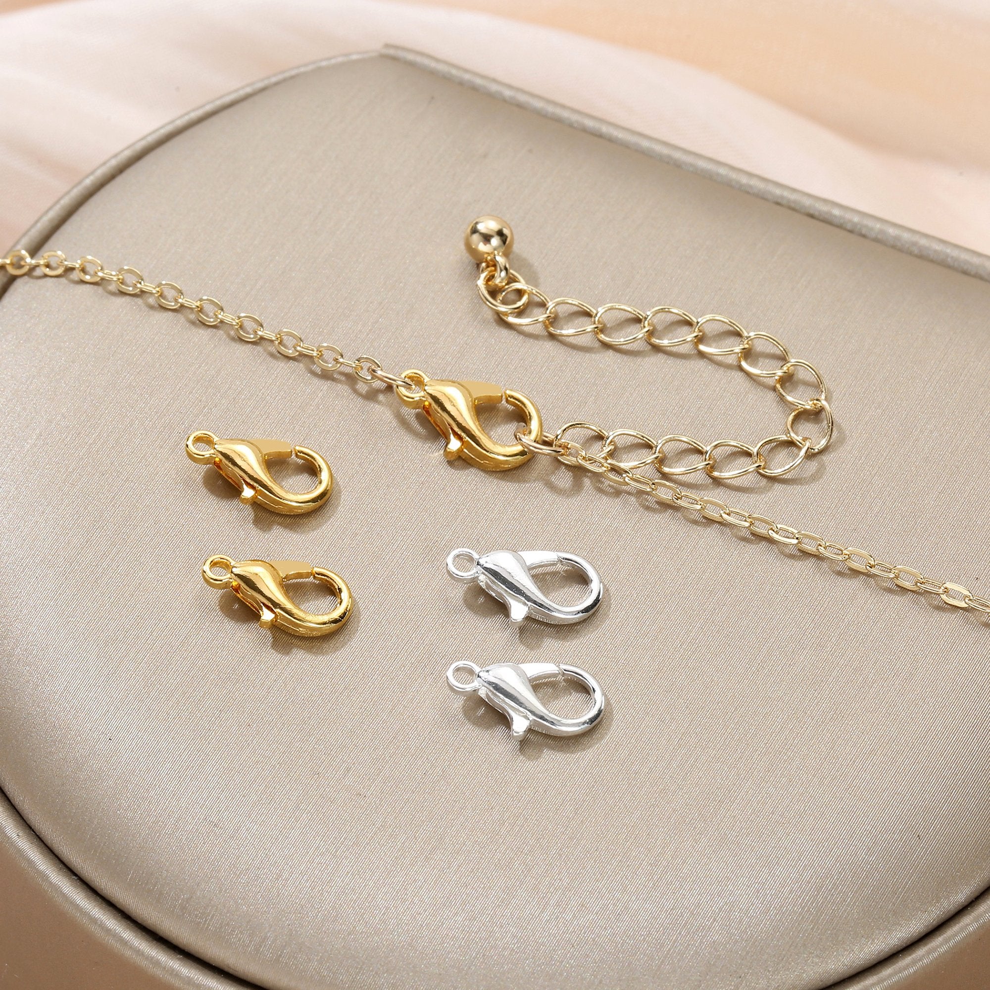Gold and silver lobster clasps and chain on a textured surface