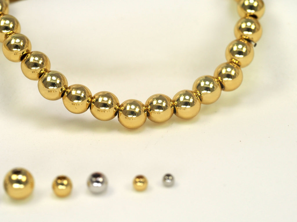 Gold filled round spacer beads and various sized beads on a white background