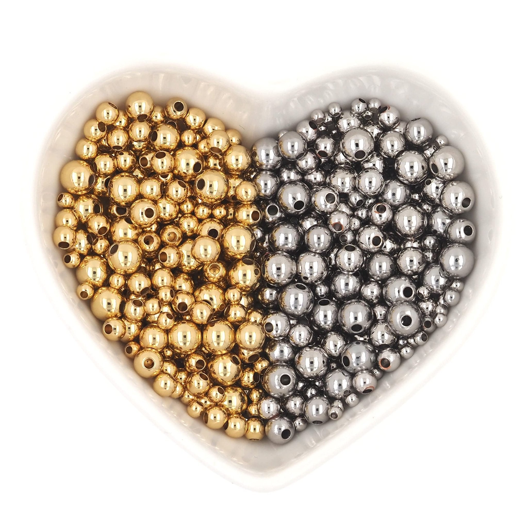 Heart-shaped dish filled with gold and silver round spacer beads for jewelry making