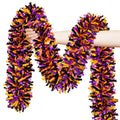 Hand holding orange, black, and purple metallic Halloween tinsel garland against a white background