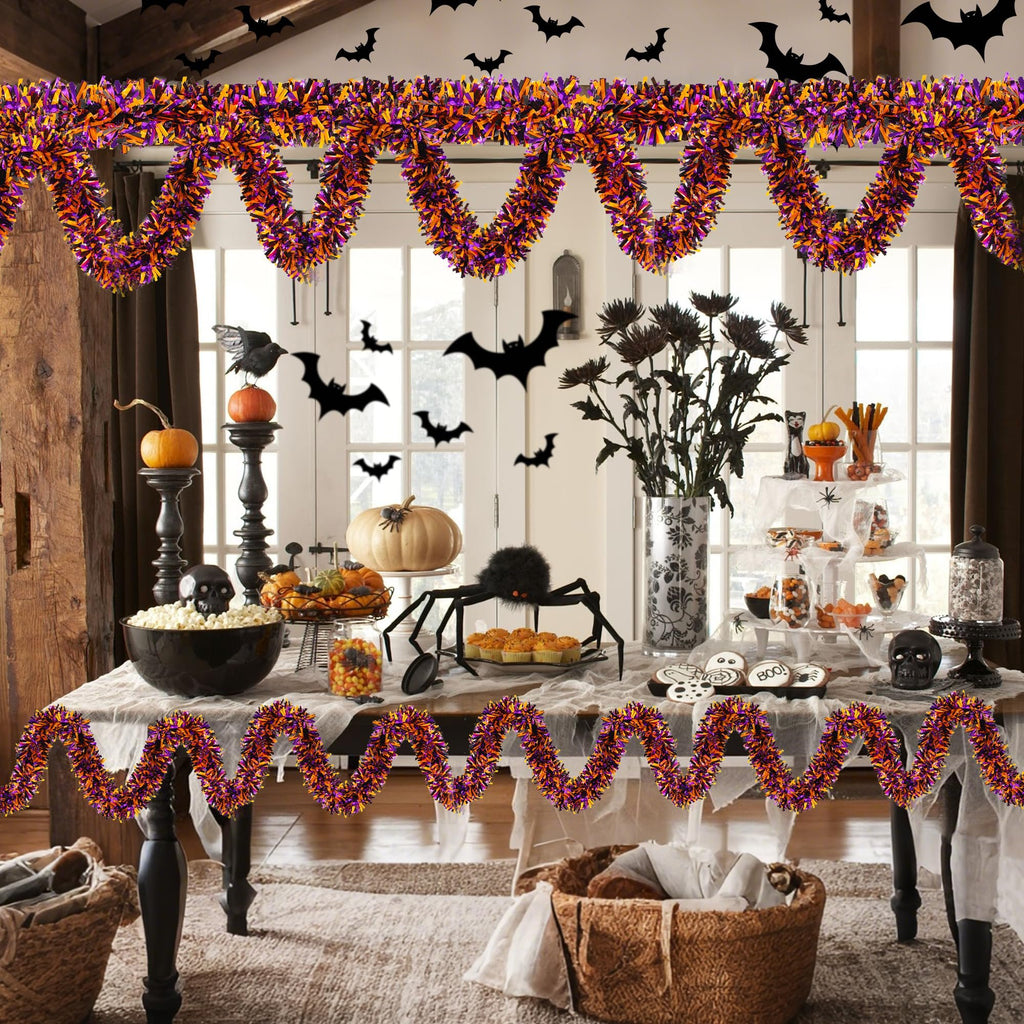 Halloween party table decorated with orange, black, and purple tinsel garland, pumpkins, spider, and cookies.