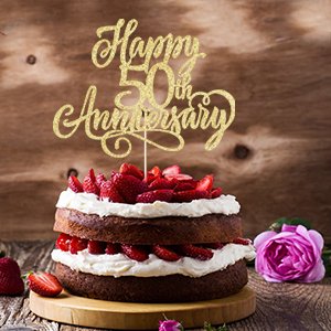 Golden glitter 'Happy 50th Anniversary' cake topper on a chocolate cake with strawberries and cream.