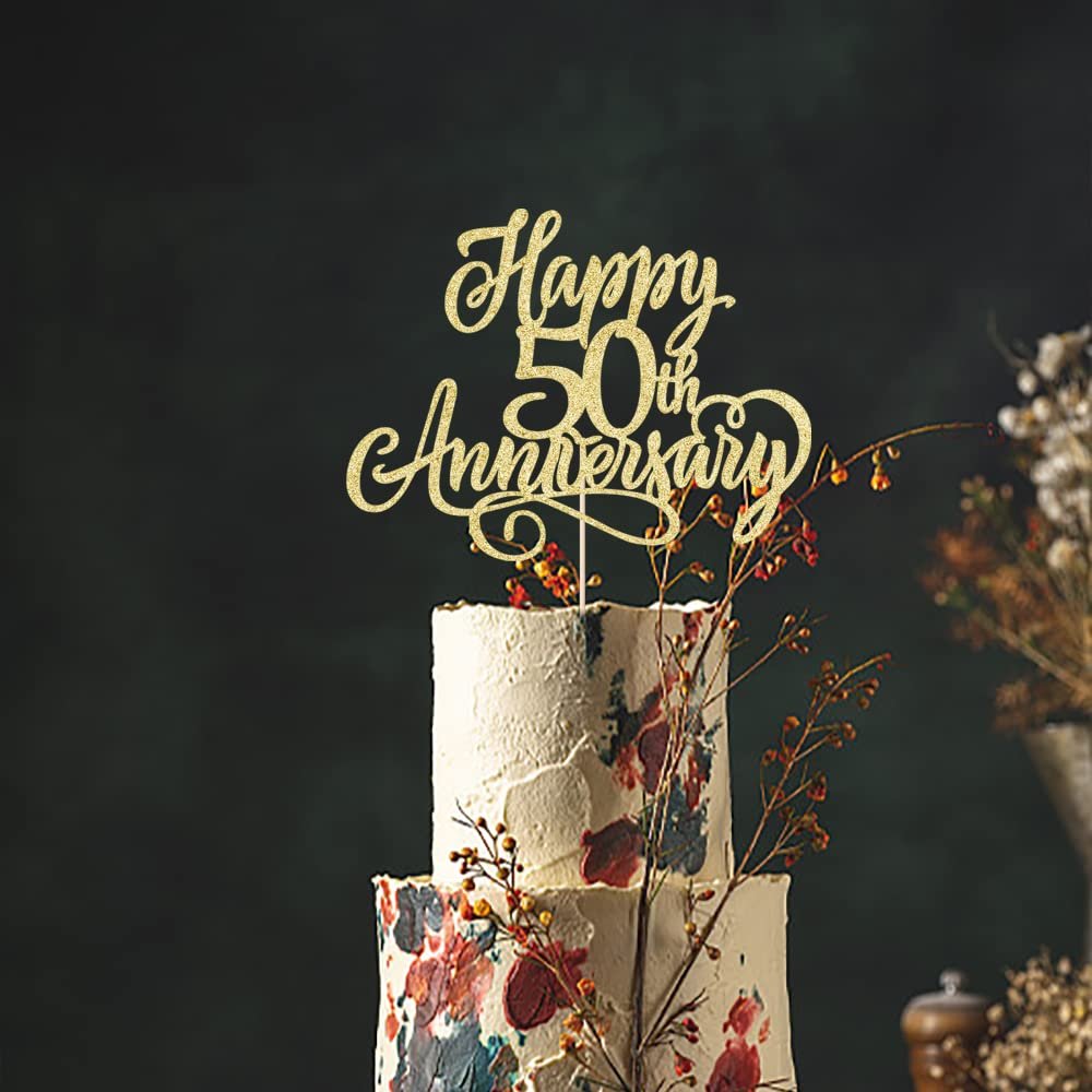Golden glitter cake topper reading 'Happy 50th Anniversary' on a two-tier cake with floral decorations.