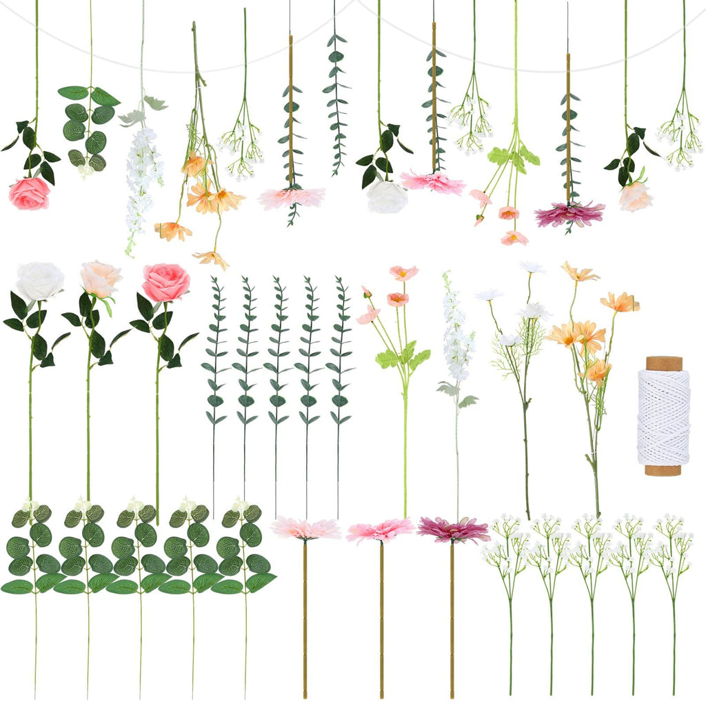 Artificial flowers and greenery with a spool of white twine on a white background