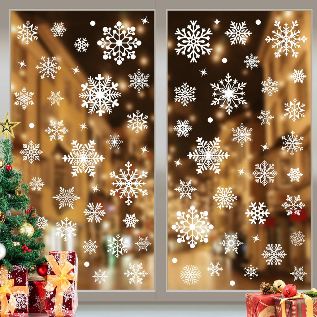 White snowflake window clings applied to a window with a blurred festive background, next to a decorated Christmas tree and gifts.