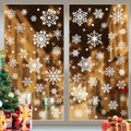 White snowflake window clings applied to a window with a blurred festive background, next to a decorated Christmas tree and gifts.