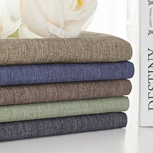 Stack of five folded fabric tablecloths in various colors, with a book on the right.