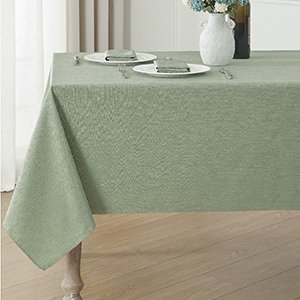 Sage green linen textured tablecloth set on a dining table with plates and napkins.