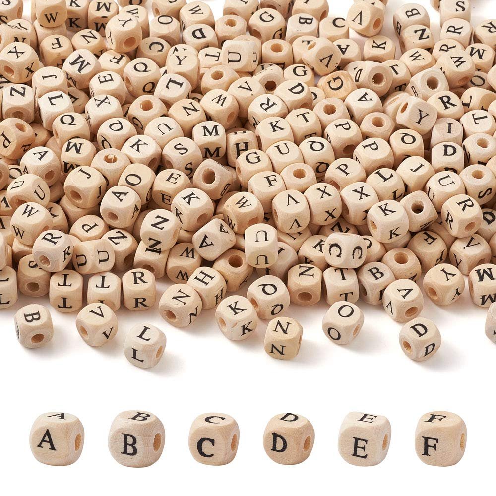 Natural wood cube alphabet beads scattered and displayed in rows, showing various letters printed on each side.
