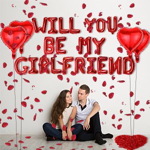 Couple sitting on floor surrounded by red rose petals and heart-shaped balloons, with 'WILL YOU BE MY GIRLFRIEND' balloon letters.
