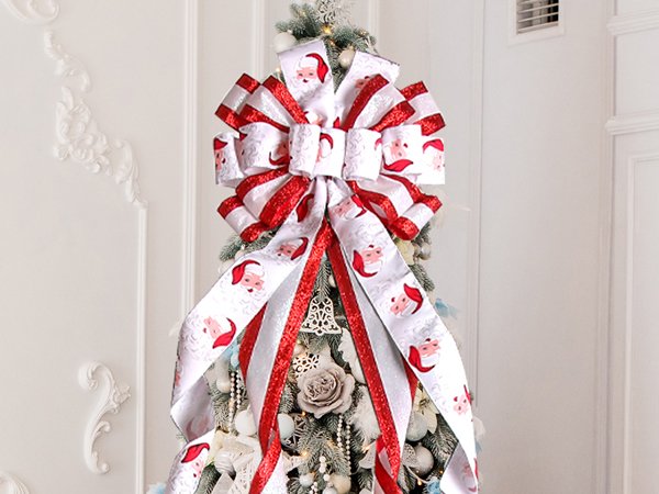 Large red and white Christmas tree topper bow with Santa Claus pattern and glittery red trim, attached to a decorated tree.