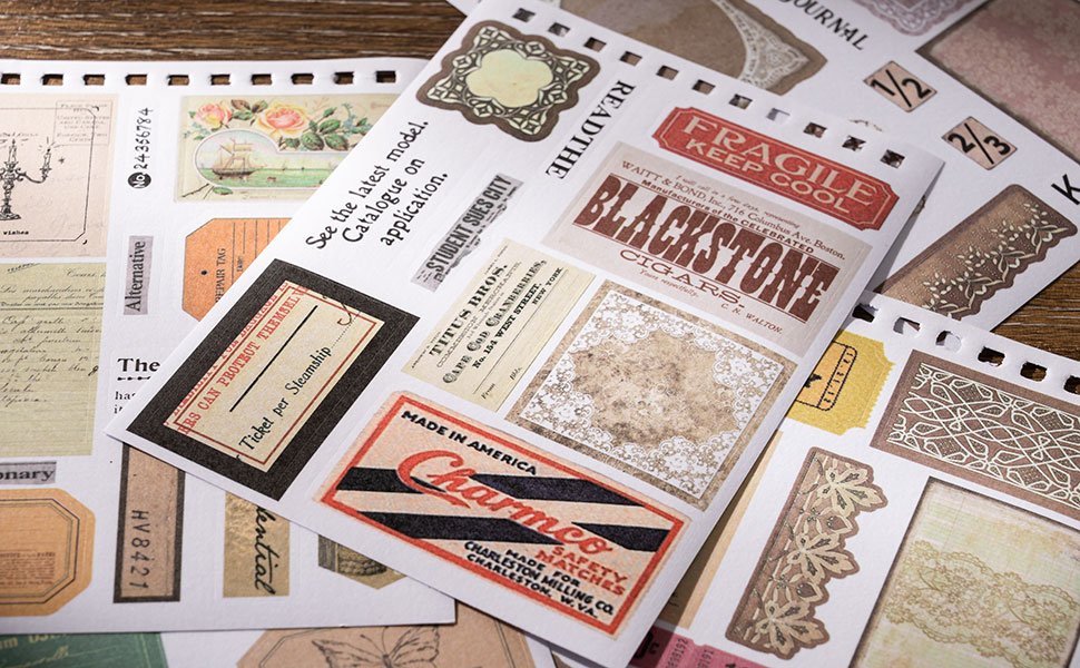 Vintage scrapbook stickers with various designs including labels, tickets, and decorative borders, laid out on a wooden surface.