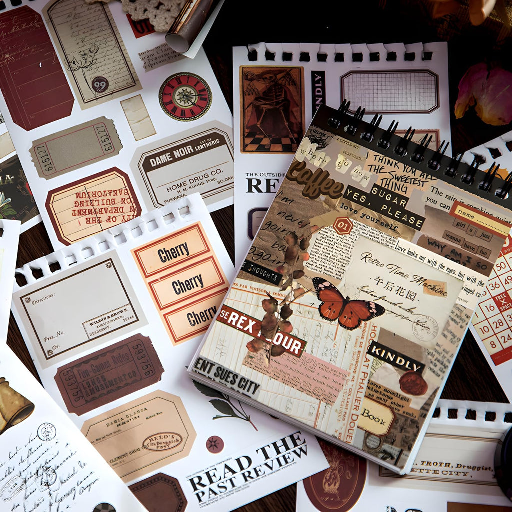 A flat lay of vintage-style scrapbook stickers and a spiral-bound notebook with various text and imagery.