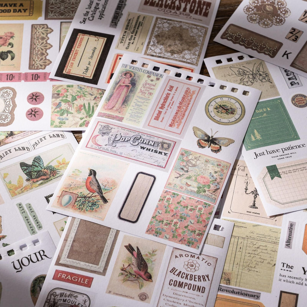 Collection of vintage-style scrapbook stickers featuring birds, butterflies, flowers, and text on a wooden surface.