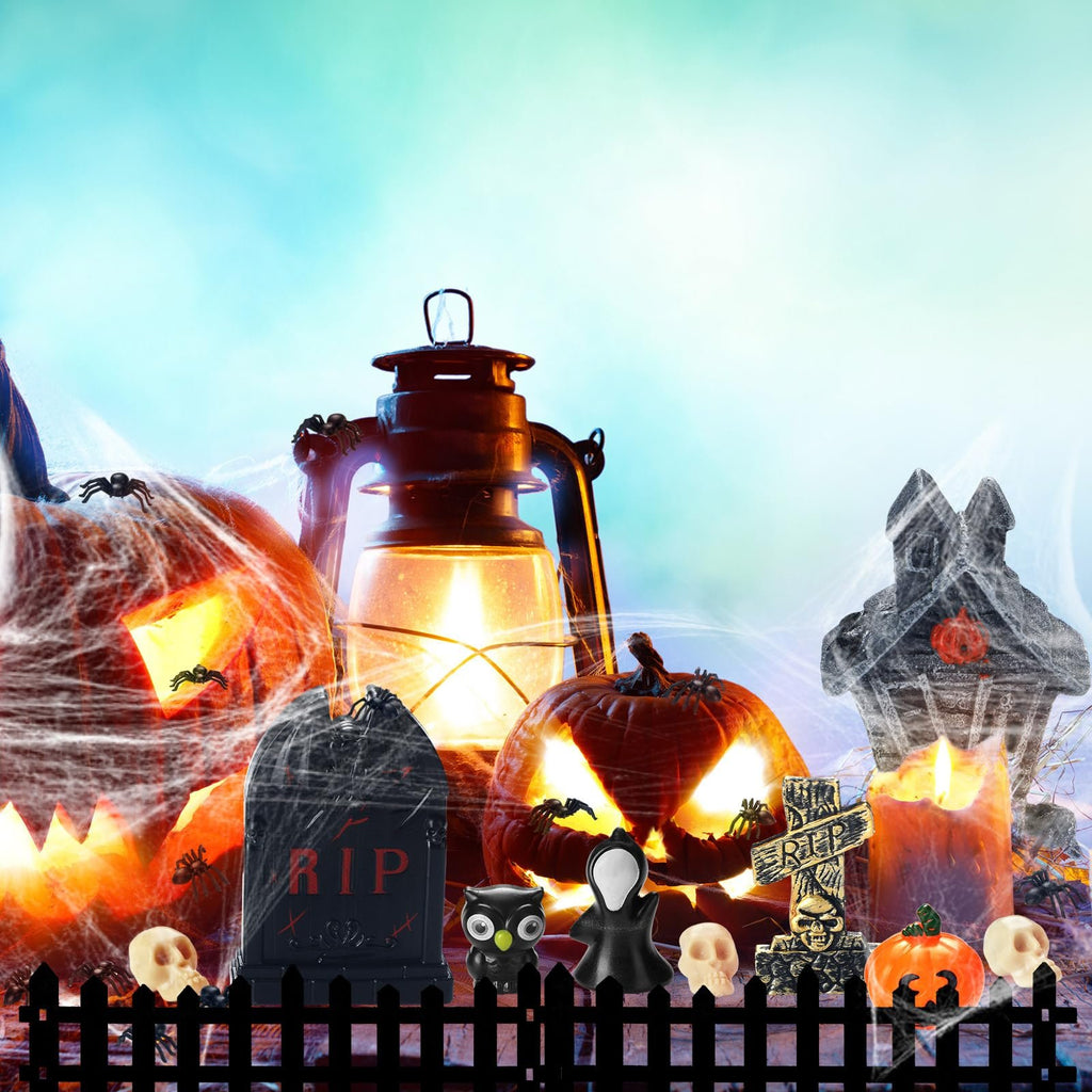 Halloween village accessories including jack-o'-lanterns, a lantern, tombstones, skulls, and a fence against a blurred blue and green background.