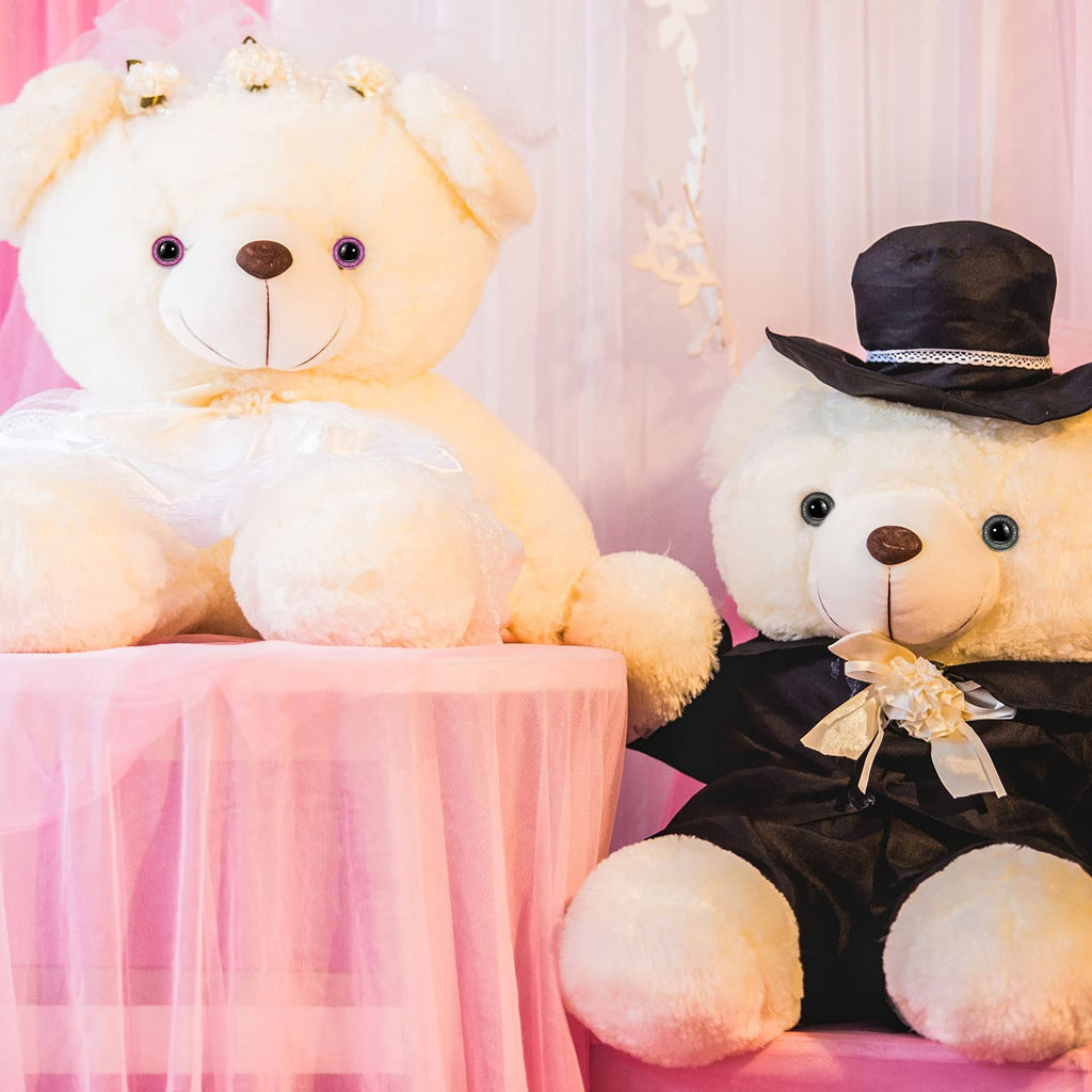 Two teddy bears dressed as a bride and groom, one wearing a veil and the other a top hat and tuxedo.