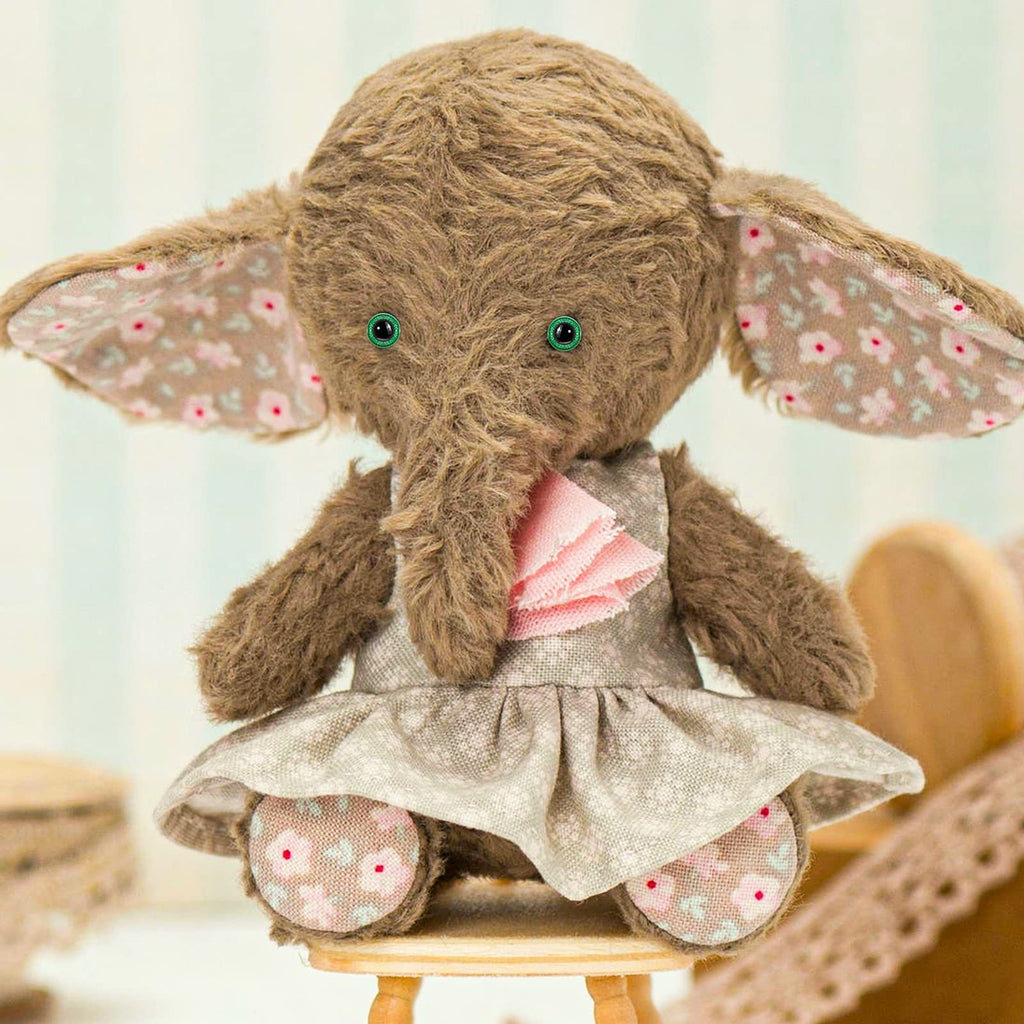 Plush elephant toy wearing a floral dress and sitting on a stool