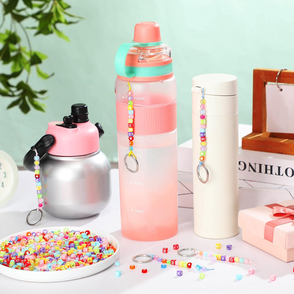DIY bead keychain kit with colorful letter and shape beads scattered around water bottles and a gift box.
