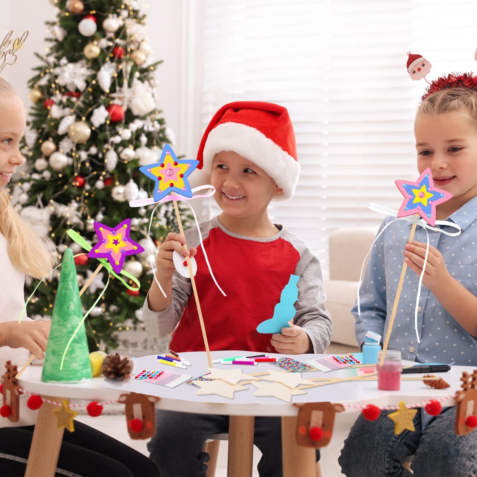 Three children crafting star wands at a table with a Christmas tree in the background.