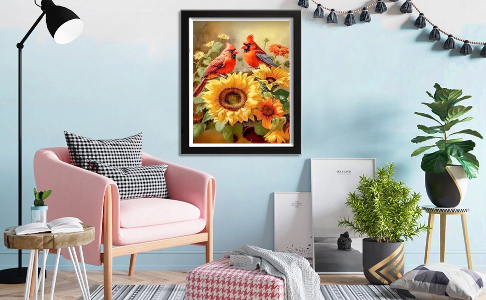 Framed diamond painting of two cardinals perched on sunflowers, displayed in a living room setting.