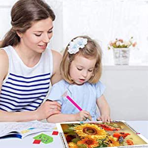 Mother and daughter working on a 5D cardinal and sunflower diamond painting kit at a table.