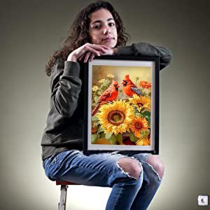 Woman holding framed 5D cardinal and sunflower diamond painting kit artwork