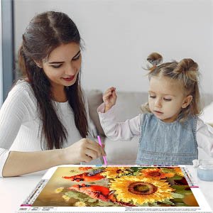 Woman and child doing a cardinal and sunflower diamond painting kit at a table